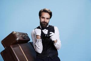 Hotel concierge wins gameplay on camera, gaming using remote controller and feeling cheerful about competition success. Confident gamer and bellboy plays online challenge. photo