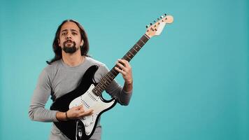 Talented person playing rock music with electric guitar, isolated over studio backdrop. Musician using musical instrument, having fun doing concert, producing entertaining songs, camera B photo
