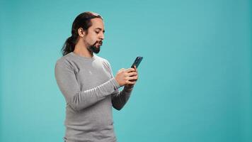 Smiling man having friendly conversation with friends during teleconference meeting using smartphone, studio background. Person having fun catching up with mates during online videocall, camera B photo