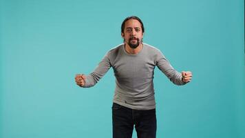Portrait of irate man feeling outraged, yelling at friend, releasing pent up emotion, studio backdrop. Furious person full of rage screaming at mate isolated over blue studio background, camera A photo