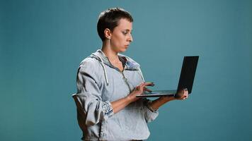 Casual woman browsing web on her laptop for freelance work in studio, remote network. Wireless computer user blogging on a new interface, trendy modern tech person. Camera A. photo