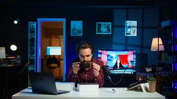 Tech guru reviewing latest phone, filming internet show in neon lights studio, shooting technology vlog using professional microphone. Vlogger presenting best smartphones on the market, camera B photo