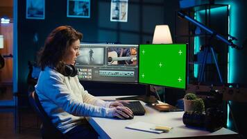 Videographer uses editing software on chroma key computer to assemble footage into final product. Woman color correcting clips on isolated screen PC to ensure project meets desired aesthetic, camera B photo