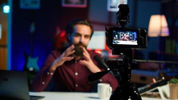 Focus on professional camera used by man in blurry background hosting online show in neon lit studio. Close up of high tech gear used by vlogger during streaming service broadcast, camera A photo