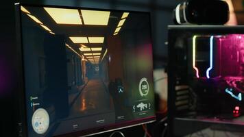 Computer screen showing first person shooter game left open at night in empty apartment with neon lights. Close up of PC on desk in living room with no people in and display left open photo