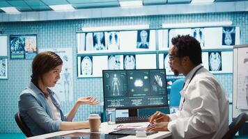 Doctor reading x ray imaging for a diagnostic report at consultation, discussing with a patient about medicine. Physician examining lab test results and analysis, health insurance. Camera B. photo