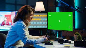Photo editor working in independent production company using green screen monitor and graphic tablet. Photographer adjusting white balance on overexposed pictures on mockup desktop computer, camera A