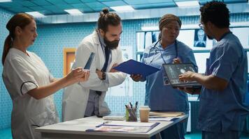 Medical professionals review x ray results and discuss patient care strategies during a meeting. Team of licensed healthcare experts working to provide accurate diagnosis in a clinic. Camera B. photo