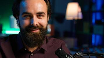 Portrait of content creator using high tech quality mic in studio to do ASMR , discussing with viewers. Smiling man using professional microphone to record podcast, camera A close up photo
