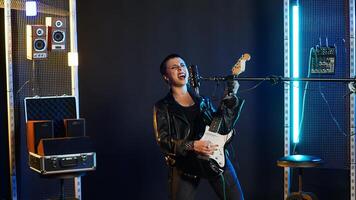 Fierce rock singer performs live singing into the microphone with passion. Cool edgy artist with rebellious energy creating a wild iconic performance in the heavy metal music industry. Camera B. photo
