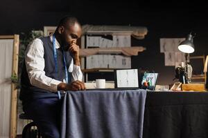 African american suitmaker overthinking in tailoring studio, working on custom made stylish business suit. Fashion designer struggling for ideas for upcoming runway show collection photo