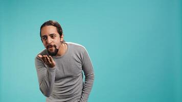 Frisky playful man blowing kisses to camera, being flirty. Lively charming person having fun sending air kisses, doing romantic gesturing, isolated over studio background, camera B photo
