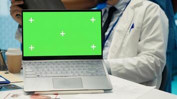 Group of doctors consulting hospital records next to chroma key display, using x ray test results to examine the diagnosis. Diverse experts meeting at clinic to provide a treatment plan. Camera A. photo