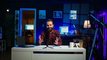 Content creator adjusting professional microphone in studio before starting vlog, recording with selfie camera. Man in neon lit home studio preparing equipment, filming with smartphone, camera B photo