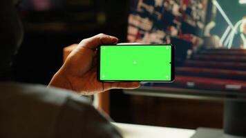 Man watching favorite content creator on isolated screen smartphone showing tips for game he is currently playing. Player looking online for inspiration on mockup phone, stuck on mission photo