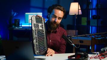 Influencer in studio reviewing gaming keyboard, mouse and headphones. Online show host filming electronics haul, presenting wired computer peripherals to viewers during live broadcast, camera A photo