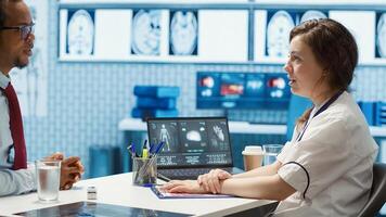 Physician meets with a patient to discuss medical results in a cabinet, using advanced diagnostic equipment to interpret x ray scans, demonstrating a professional healthcare approach. Camera A. photo