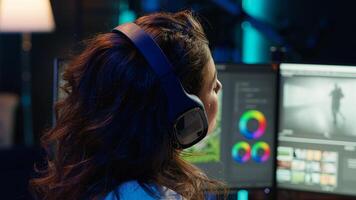Freelancer adds sound effects to filmed footage, working in home studio. Post production specialist using headphones to test and improve audio quality using editing application, camera A photo