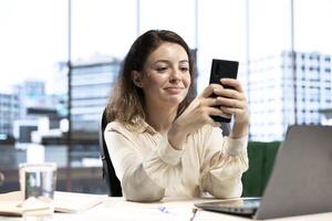 Female CEO discussing business ideas with her team on social media, receiving project updates form employees via text messages. Successful goal oriented entrepreneur with determination. photo