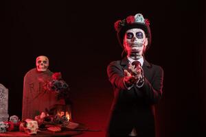 Portrait of mysterious lady doing provocative luring gesturing at Dia de los Muertes indigenous rites. Woman doing enticing hand invitation at Day of the Dead celebration in honor of the deceased photo