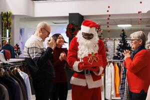 Retail worker reading names on papers to announce winner of december raffle contest in shopping mall, giving prize to client during christmas holiday. Diverse people waiting to see who won. photo