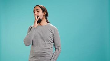 Portrait of bored man lacking enthusiasm to do anything, yawning, wasting time, isolated over studio background. Lazy person living monotonous life, having sleepy dull facial expression, camera B photo