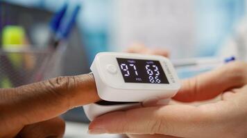 Medical specialist takes the oxygen saturation measurement and checking vital signs during a routine check up with her patient. Medic using an oximeter for accurate readings in office. Camera B. photo