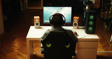 Man playing SF videogame on PC screen, shooting asteroids, putting headphones on. Close up of gamer enjoying spaceship flying game on computer desktop display, navigating through meteorites, camera B photo