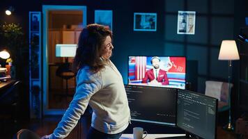 Programmer doing software quality assurance, stretching arms behind back after reading source code, feeling fatigued. IT expert takes break from work to relax muscles after inspecting coding, camera B photo
