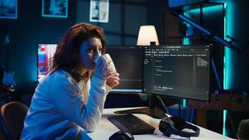 Portrait of smiling IT specialist drinking coffee while looking for company security vulnerabilities and preventing malware infections. Programmer enjoying hot beverage while writing code, camera B photo