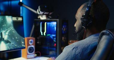 Man wearing headphones playing game, teaching subscribers professional esport skills, close up shot. Media star using headset mic to chat with viewers, filming gaming tutorial, camera B photo