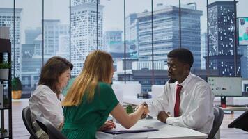 New employee signing his work contract after successful job interview with the HR staff, businesswomen shaking hands and welcoming man to the team. Job applicant securing a position. Camera B. photo