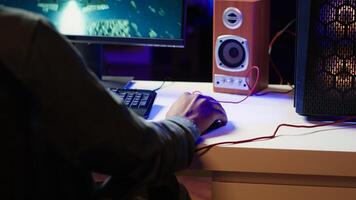 Player using keyboard and mouse to play videogame on gaming PC in neon lit apartment. Gamer using high tech computer peripherals to destroy enemies, relaxing at home, camera A photo