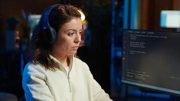 Admin listening music and writing lines of code filtering malicious traffic from cybercriminals attempting to steal company data. Woman wearing headphones while preventing malware, camera A photo