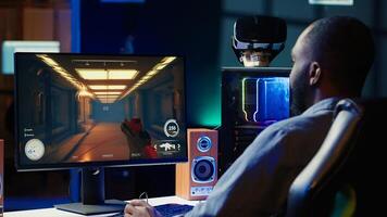 Man arriving at home to play videogames on gaming PC at computer desk, enjoying day off from work. Gamer entering room, battling enemies in online multiplayer shooter, camera A photo