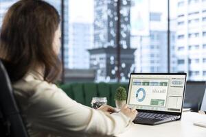 Young CEO searching for an investment solution and the right offer, avoiding trading risks and using funds to increase company profit. Female director planning finances in high end office. photo