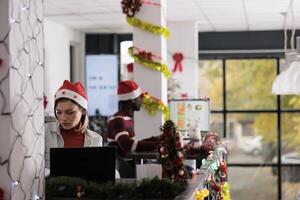 Skillful multiethnical team working in busy xmas adorn modern office during holiday season. Focused coworkers solving business tasks in decorated workplace before Christmas photo