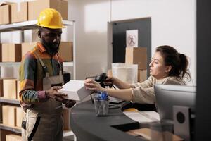 Storehouse supervisor scanning white carton box using store scanner, discussig shipping detalis with african american employee. Diverse team working at merchandise quality control in warehouse photo