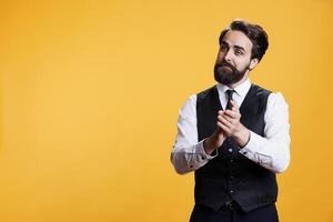 Friendly waiter clapping hands for person, trying to boost confidence and celebrate success in studio. Professional employee at restaurant applauding someone and presenting his congratulations. photo