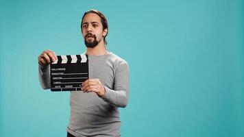 Movie director using clapper to signal actors beginning of scene recording, studio background. Film producer on set filming production, using clapperboard, camera B photo