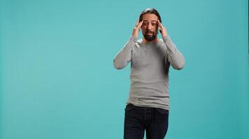 Portrait of man feeling exhausted from overworking, suffering from headache, isolated over studio background. Tired person feeling pain from fatigue, studio backdrop, camera A photo