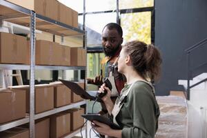 Stockroom supervisor showing box with customer order while manager scanning packages barcode using store scanner in storehouse. Diverse colleagues working at merchandise inventory in warehouse photo