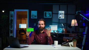 Man showing green screen cellphone, using it as empty copy space to showcase his online streaming channel logo. Media star does introductory using chroma key phone, camera B photo