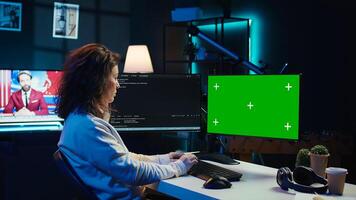 Developer doing software debugging on green screen PC at home, checking lines of code displayed on monitors. IT professional in living room fixing coding problems on mockup computer, camera B photo