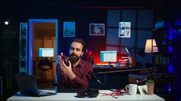 Influencer in studio reviewing gaming keyboard, mouse and headphones. Online show host filming electronics haul, presenting wired computer peripherals to viewers during live broadcast, camera B photo