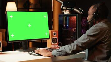 Gamer using keyboard and mouse to play videogame on gaming PC isolated screen monitor. Man in apartment at night using high tech computer peripherals to defeat foes on mockup display photo
