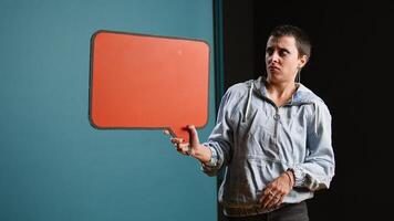 Casual person presenting an empty speech bubble sign in studio, working on a commercial with billboard icon. Woman holding cardboard for advertisement against background. Camera A. photo