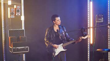 Confident musician performing live in a spotlight illuminated studio, surrounded by audio equipment and lights. Rocker doing a live performance in a rebellious style, bold attitude. Camera B. photo
