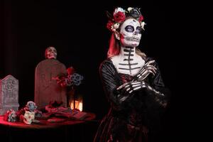 Woman with flower wreath on head at Day of the Dead event to remember the deceased, celebrating their memory. Lady wearing gothic corpse makeup for holiday of remembrance for those who have passed photo