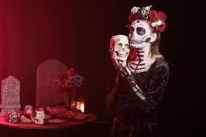 Woman posing with skull in hand, doing Hamlet scene, doing indigenous rites of honoring the dead during Dia de los Muerte. Actress doing theatre play during Day of the Dead in honor of the deceased photo